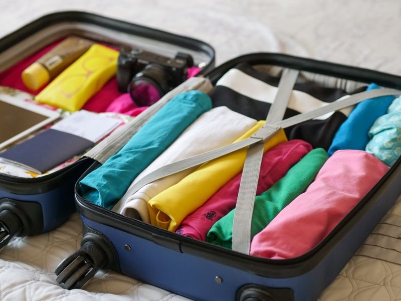 Open suitcase packed with rolled, organised clothes