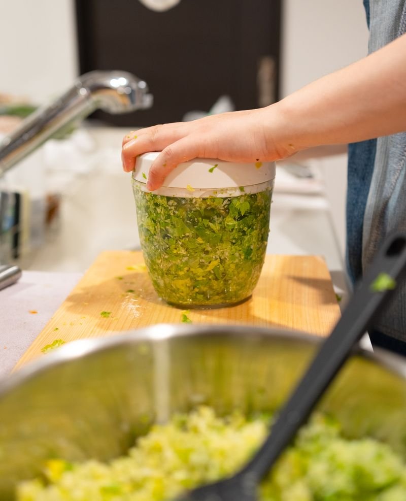 Hands chopping fresh herbs and vegetables on a kitchen board